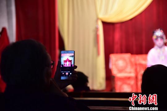 一位观众使用手机拍摄演员的表演。　林馨摄