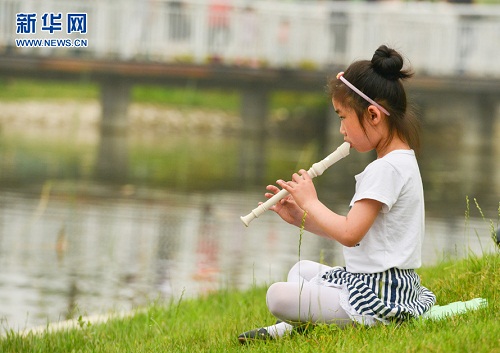 在湖边演奏竖笛的小朋友